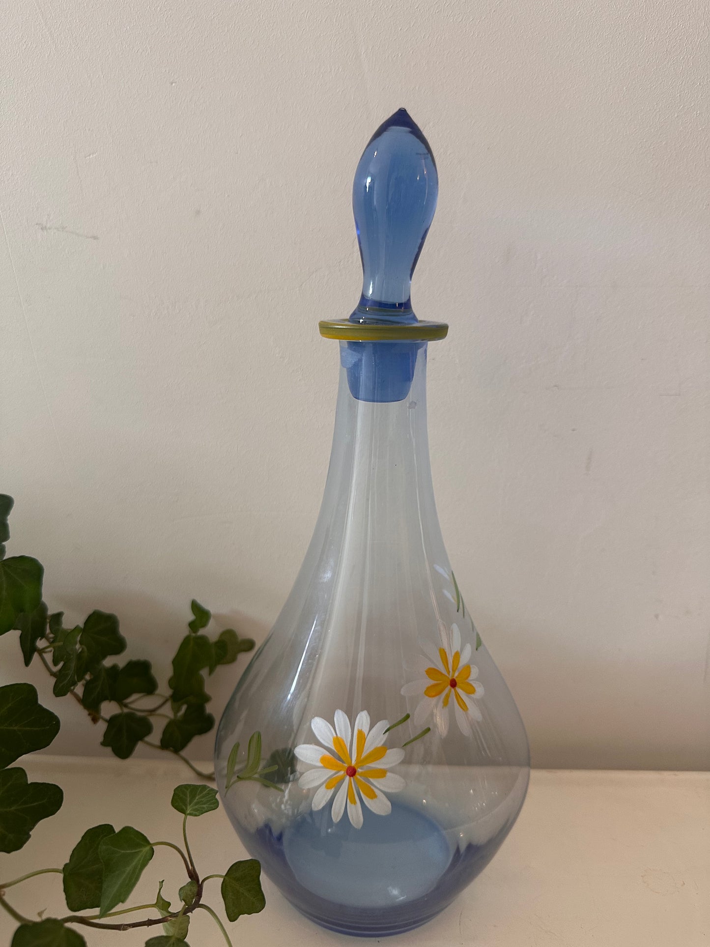 Karaf van blauw glas met margrietjes