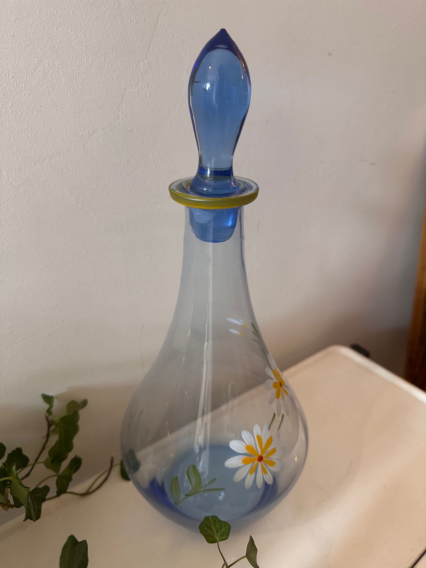 Karaf van blauw glas met margrietjes