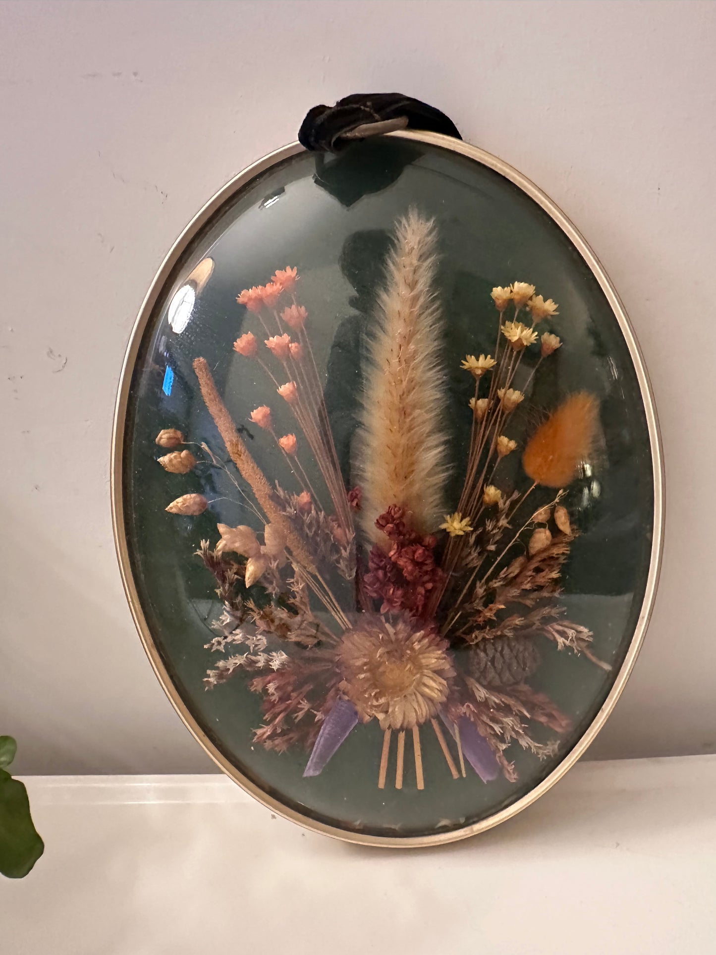 Wanddecoratie van droogbloemen achter gebold glas