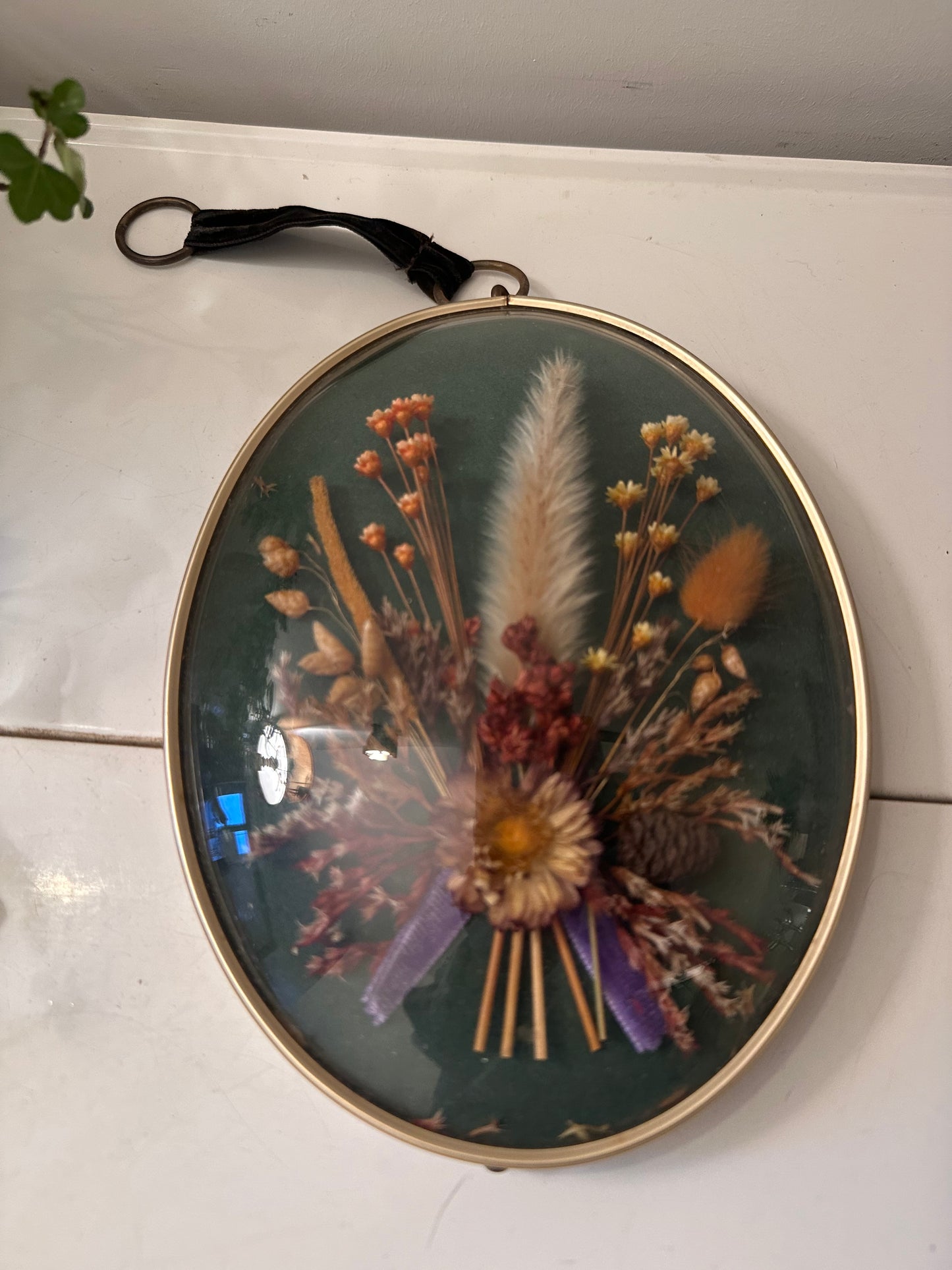 Wanddecoratie van droogbloemen achter gebold glas