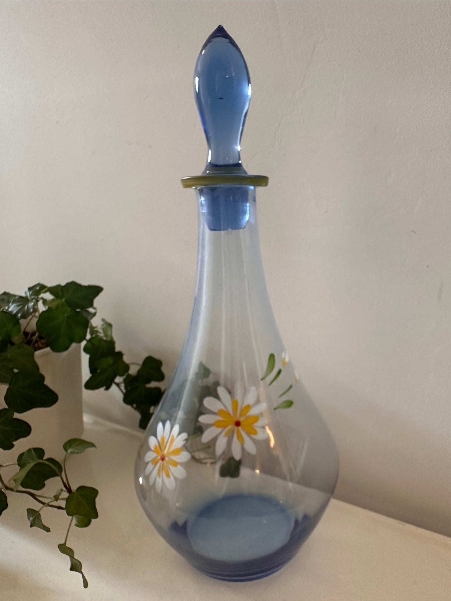 Karaf van blauw glas met margrietjes