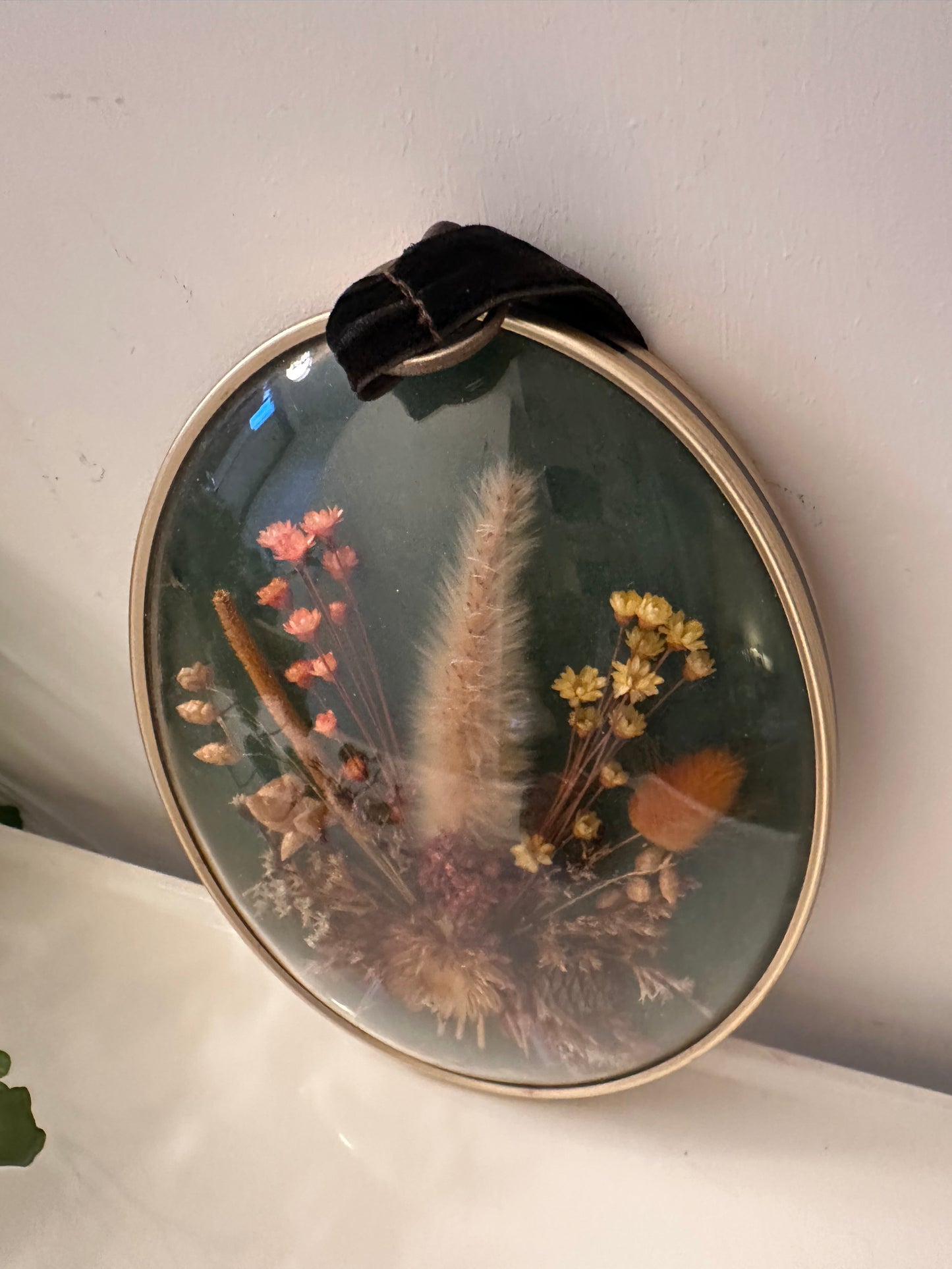 Wanddecoratie van droogbloemen achter gebold glas